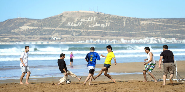 Sechs Männer spielen Fußball am Strand Sechs Männer spielen Fußball am Strand