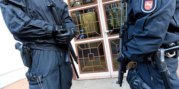 Zwei Polizisten stehen mit Waffen in der Hand vor einer Tür Zwei Polizisten stehen mit Waffen in der Hand vor einer Tür