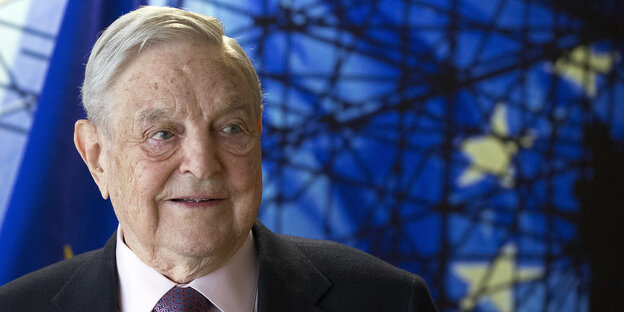 George Soros steht vor einer Flagge der EU George Soros steht vor einer Flagge der EU