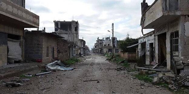 Eine Straße und am Rand zerstörte, verlassene Gebäude Eine Straße und am Rand zerstörte, verlassene Gebäude