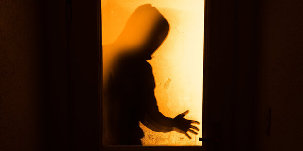Schatten einer Person hinter einer Glastür Schatten einer Person hinter einer Glastür