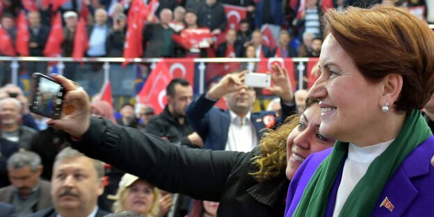 Eine Frau macht mit einer anderen ein Selfie, im Hintergrund türkische Flaggen Eine Frau macht mit einer anderen ein Selfie, im Hintergrund türkische Flaggen