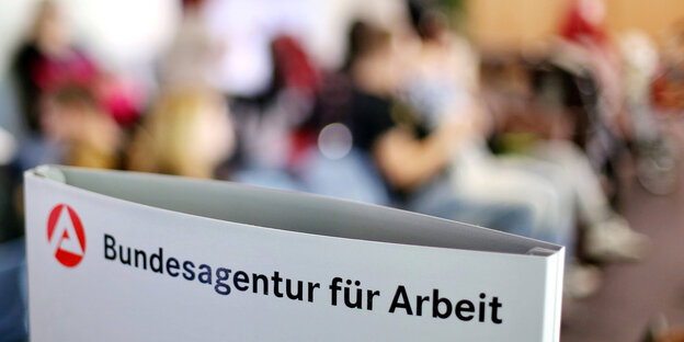 Schild vor vollem Wartezimmer von Arbeitsagentur