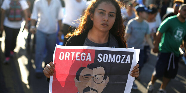 Eine junge Frau hält ein Plakat in den Händen, auf dem Ortega mit Somoza verglichen wird Eine junge Frau hält ein Plakat in den Händen, auf dem Ortega mit Somoza verglichen wird