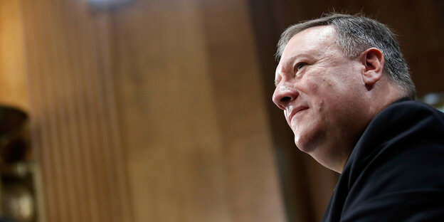 Mike Pompeo spricht bei Anhörung, im Hintergrund zwei Frauen