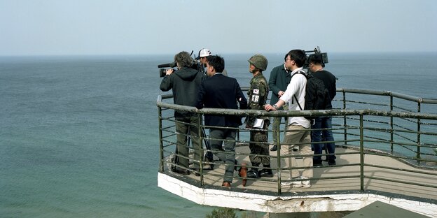 Personen drängen sich auf Plattform über dem Meer Personen drängen sich auf Plattform über dem Meer