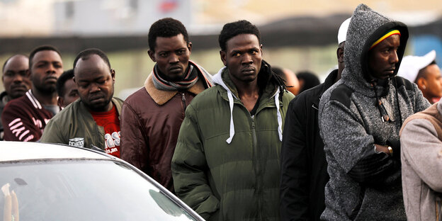 Afrikanische Migranten warten in einer Schlange neben einem Auto vor israelischen Behörden Afrikanische Migranten warten in einer Schlange neben einem Auto vor israelischen Behörden
