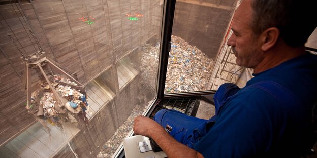 Ein Arbeiter schaut in einen Müllbunker Ein Arbeiter schaut in einen Müllbunker