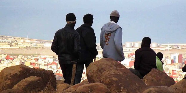 Fünf Personen blicken von einem Hügel auf die Stadt Melilla. Fünf Personen blicken von einem Hügel auf die Stadt Melilla.