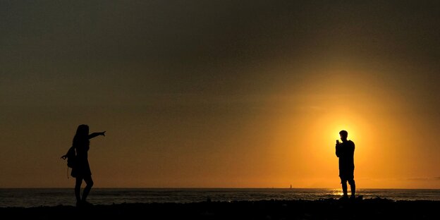 Mann und Frau am Strand bei Sonnenaufgang Mann und Frau am Strand bei Sonnenaufgang