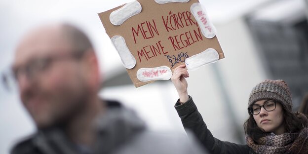 Paragraf 219a: Eine Frau demonstriert mit einem Schild auf dem steht: Mein Körper meine Regeln