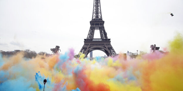 Menschen bewerfen sich vor dem Eiffelturm in Paris mit bunten Farben Menschen bewerfen sich vor dem Eiffelturm in Paris mit bunten Farben