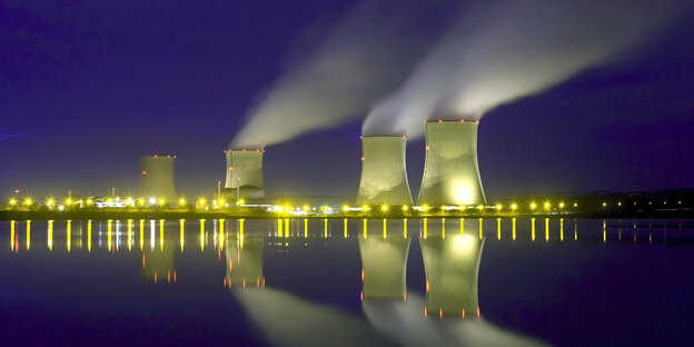 Ein Atomkraftwerk am Wasser, aus dessen Türmen Rauch aufsteigt Ein Atomkraftwerk am Wasser, aus dessen Türmen Rauch aufsteigt