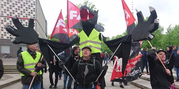 Drei Männer halten FAu-Flaggen und eine Figur in die Luft Drei Männer halten FAu-Flaggen und eine Figur in die Luft
