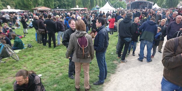 Menschen stehen auf einer Wiese herum Menschen stehen auf einer Wiese herum