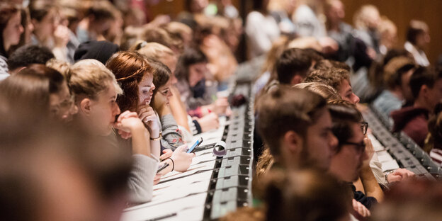 Studierende sitzen in den Bänken eines Hörsaals Studierende sitzen in den Bänken eines Hörsaals
