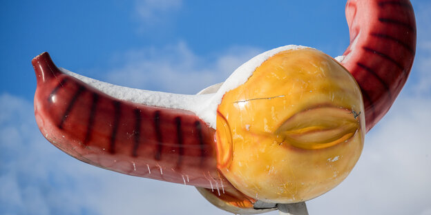 Schnee liegt auf einer großen Bratwurst, die für einen Imbisstand wirbt Schnee liegt auf einer großen Bratwurst, die für einen Imbisstand wirbt