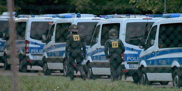 Polizisten vor Polizeiautos