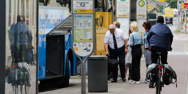 Ein Radfahrer fährt auf einem Radweg, auf dem Leute stehen, die in einen Bus einsteigen wollen. Ein Radfahrer fährt auf einem Radweg, auf dem Leute stehen, die in einen Bus einsteigen wollen.