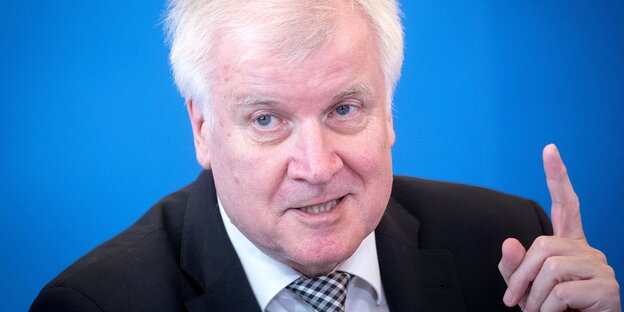 Horst Seehofer sitzt vor einem blauen Hintergrund und hebt den Zeigefinger Horst Seehofer sitzt vor einem blauen Hintergrund und hebt den Zeigefinger