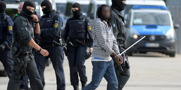 Mann mit Handschellen umringt von Polizisten Mann mit Handschellen umringt von Polizisten