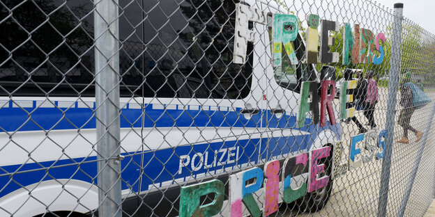 Ein großes weiß-blaues Polizeiauto steht vor einem Zaun Ein großes weiß-blaues Polizeiauto steht vor einem Zaun