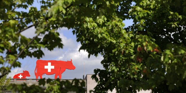 Eine Kuh-Silhouette mit Schweizer-Fahnen-Design steht auf dem Dach der Schweizer Botschaft in Berlin Eine Kuh-Silhouette mit Schweizer-Fahnen-Design steht auf dem Dach der Schweizer Botschaft in Berlin