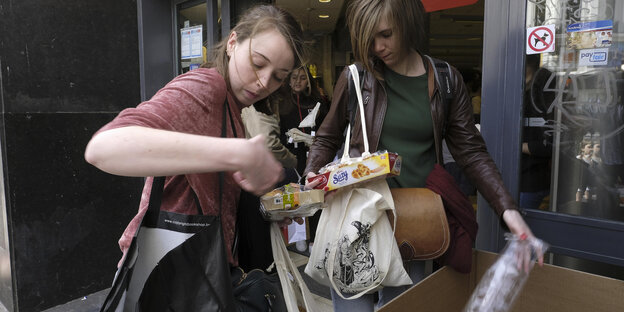 Zwei Einkäuferinnen entsorgen überflüssiges Plastik vor einem Brüssler Supermarkt Zwei Einkäuferinnen entsorgen überflüssiges Plastik vor einem Brüssler Supermarkt