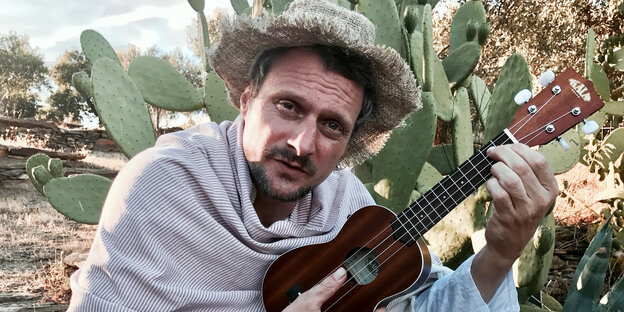 DJ Koze mit Ukulele vor Kaktus DJ Koze mit Ukulele vor Kaktus