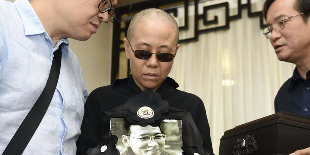 Eine Frau, Liu Xia, hält ein Foto von Liu Xiaobo in der Hand Eine Frau, Liu Xia, hält ein Foto von Liu Xiaobo in der Hand