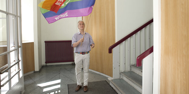 Der Friedensaktivist Reiner Braun hält eine Regenbogenfahne mit "Peace" in der Hand Der Friedensaktivist Reiner Braun hält eine Regenbogenfahne mit "Peace" in der Hand