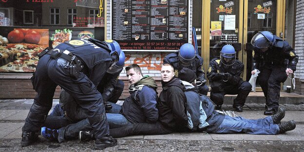 Demonstranten sitzen auf dem Boden als sie von Polizisten festgenommen werden Demonstranten sitzen auf dem Boden als sie von Polizisten festgenommen werden