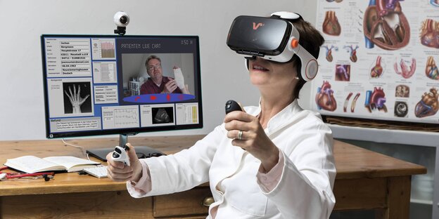Eine Ärztin sitzt vor einem Laptop, auf dem Display ist ein Patiient zu sehen. Sie trägt eine Virtual-Reality-Brille Eine Ärztin sitzt vor einem Laptop, auf dem Display ist ein Patiient zu sehen. Sie trägt eine Virtual-Reality-Brille
