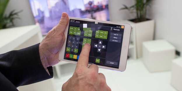 Mann hält Tablet zur Steuerung vernetzter Haushaltsgeräte Mann hält Tablet zur Steuerung vernetzter Haushaltsgeräte