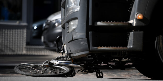 Ein Fahrrad liegt zerdellt unter einer Stoßstange. Ein Fahrrad liegt zerdellt unter einer Stoßstange.