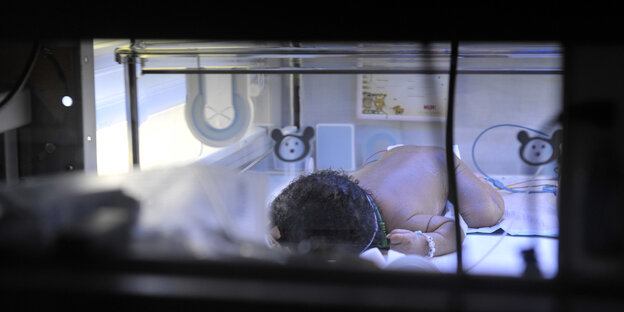 Ein neu geborenes Baby liegt mit Schläuchen am Körper in einem Krankenhausbett. Ein neu geborenes Baby liegt mit Schläuchen am Körper in einem Krankenhausbett.