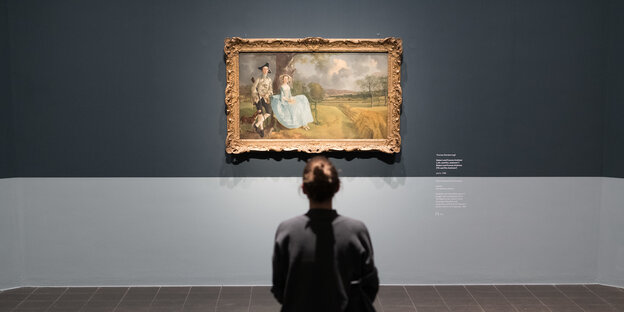 Eine Frau sitzt vor einem Bild von Thomas Gainsborough.