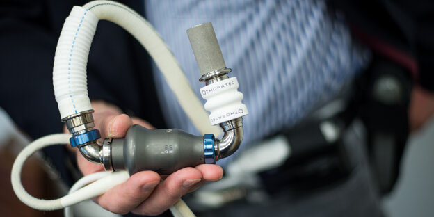 Ein Mann hält ein kleines Pumpsystem in der Hand Ein Mann hält ein kleines Pumpsystem in der Hand