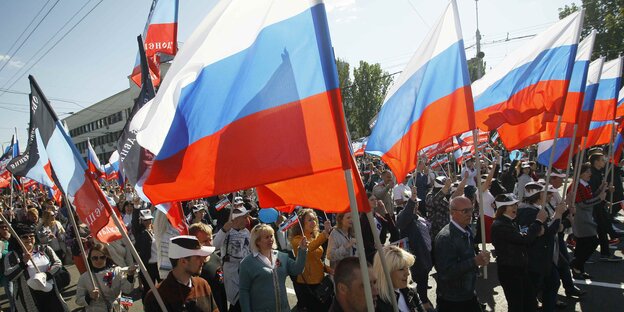 Menschen mit russischen Fahnen laufen auf der Straße Menschen mit russischen Fahnen laufen auf der Straße