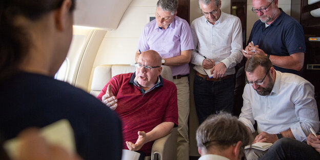 Peter Altmaier in einem Flugzeug, umringt von schreibenden Männern Peter Altmaier in einem Flugzeug, umringt von schreibenden Männern