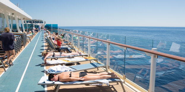 Auf dem Sonnendeck eines Kreuzfahrtschiffs liegen Menschen auf Liegen und sonnen sich. Auf dem Sonnendeck eines Kreuzfahrtschiffs liegen Menschen auf Liegen und sonnen sich.