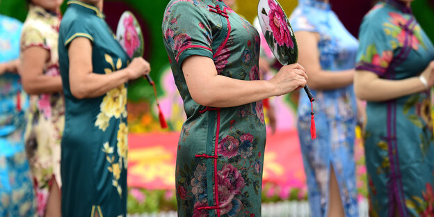 Sechs Frauen tragen verschiedenfarbige chinesische Seidenkleider und halten Fächer Sechs Frauen tragen verschiedenfarbige chinesische Seidenkleider und halten Fächer