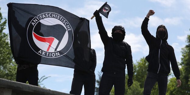 Schwarz gekleidete Menschen halten Flaggen der Antifa hoch Schwarz gekleidete Menschen halten Flaggen der Antifa hoch