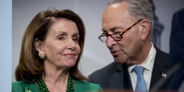 Nancy Pelosi und Chuck Schumer lachen an einem Pult Nancy Pelosi und Chuck Schumer lachen an einem Pult