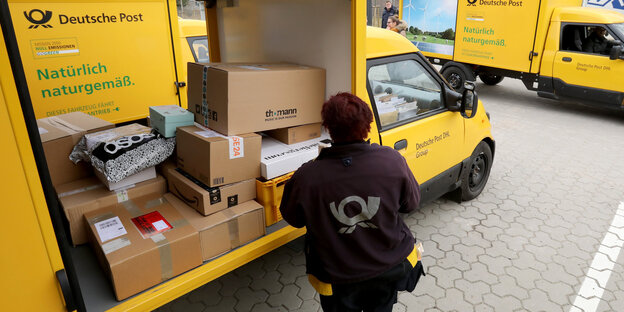 Eine Mitarbeiterin der Deutschen Post belädt einen Kleintransporter mit Paketen Eine Mitarbeiterin der Deutschen Post belädt einen Kleintransporter mit Paketen