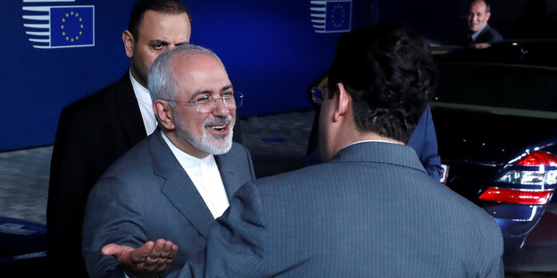 Mohammad Javad Zarif begrüßt lächelnd einen anderen Mann Mohammad Javad Zarif begrüßt lächelnd einen anderen Mann