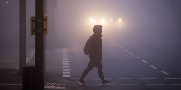 Ein Kind läuft über eine Straße. Es ist dunkel und die Sicht ist schlecht. Im Hintergrund nähert sich ein Auto Ein Kind läuft über eine Straße. Es ist dunkel und die Sicht ist schlecht. Im Hintergrund nähert sich ein Auto