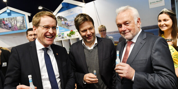 Daniel Günther, Robert Habeck und Wolfgang Kubicke stehen vergnügt nebeneinander und haben jeweils ein Fläschchen Schnaps in der Hand. Daniel Günther, Robert Habeck und Wolfgang Kubicke stehen vergnügt nebeneinander und haben jeweils ein Fläschchen Schnaps in der Hand.