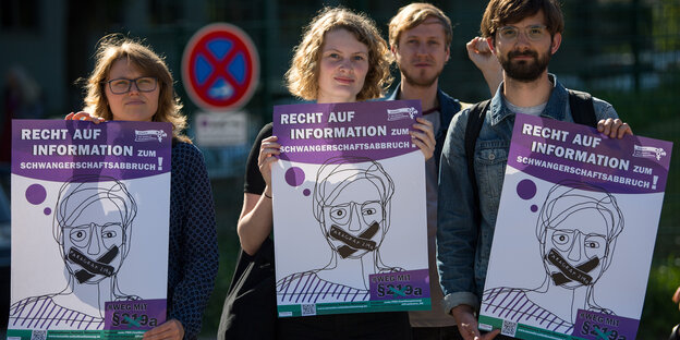 Zwei Männer und zwei Frauen halten Schilder mit der Aufschrift: Recht auf Information zum Schwangerschaftsabbruch Zwei Männer und zwei Frauen halten Schilder mit der Aufschrift: Recht auf Information zum Schwangerschaftsabbruch