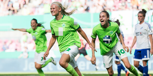 vier Fußballspielerinnen, eine im blau-weißen, drei im grünen Trikot vier Fußballspielerinnen, eine im blau-weißen, drei im grünen Trikot
